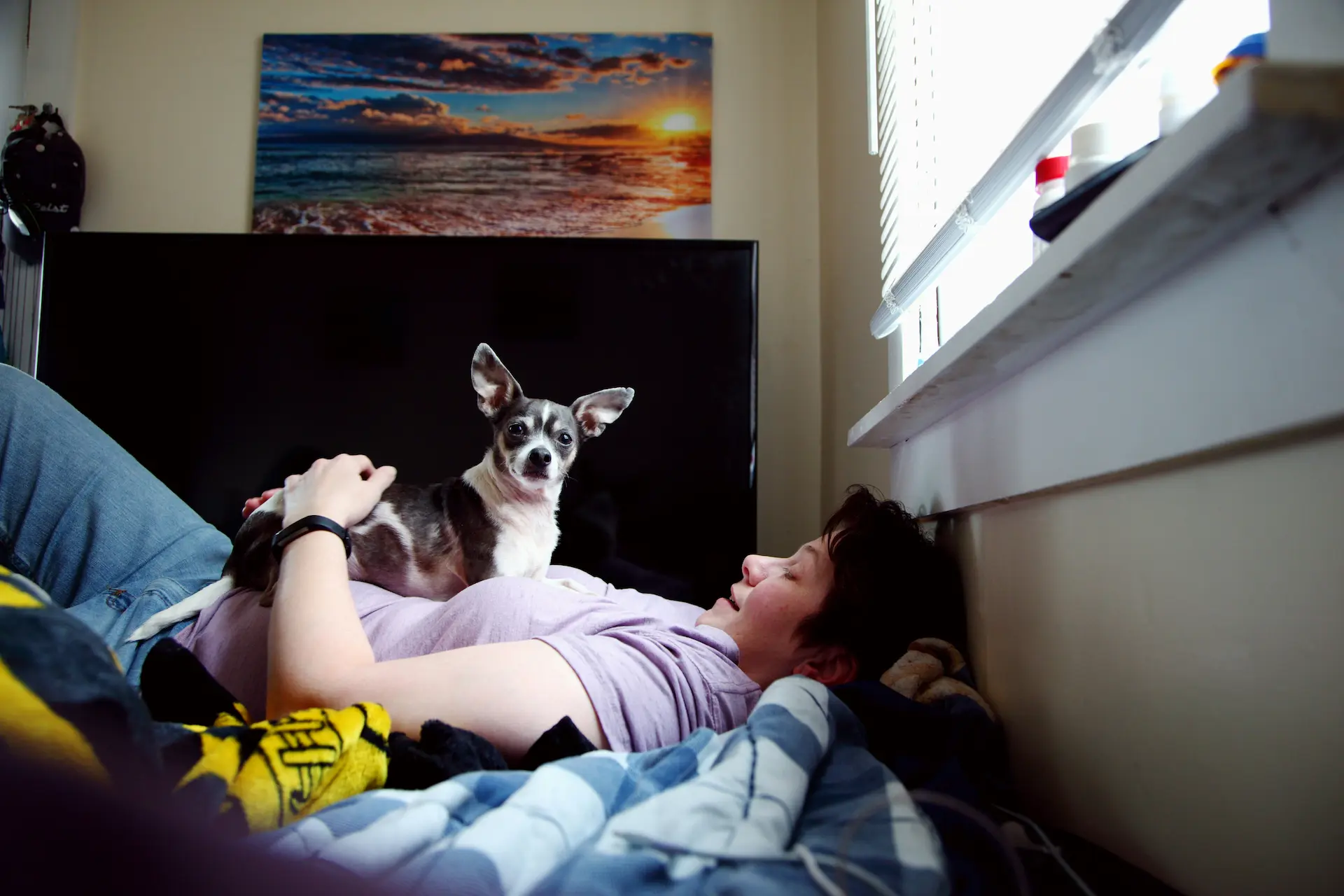 Teenager lying with a dog in bedroom